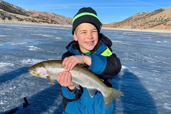 a young boy holding a fish in the water